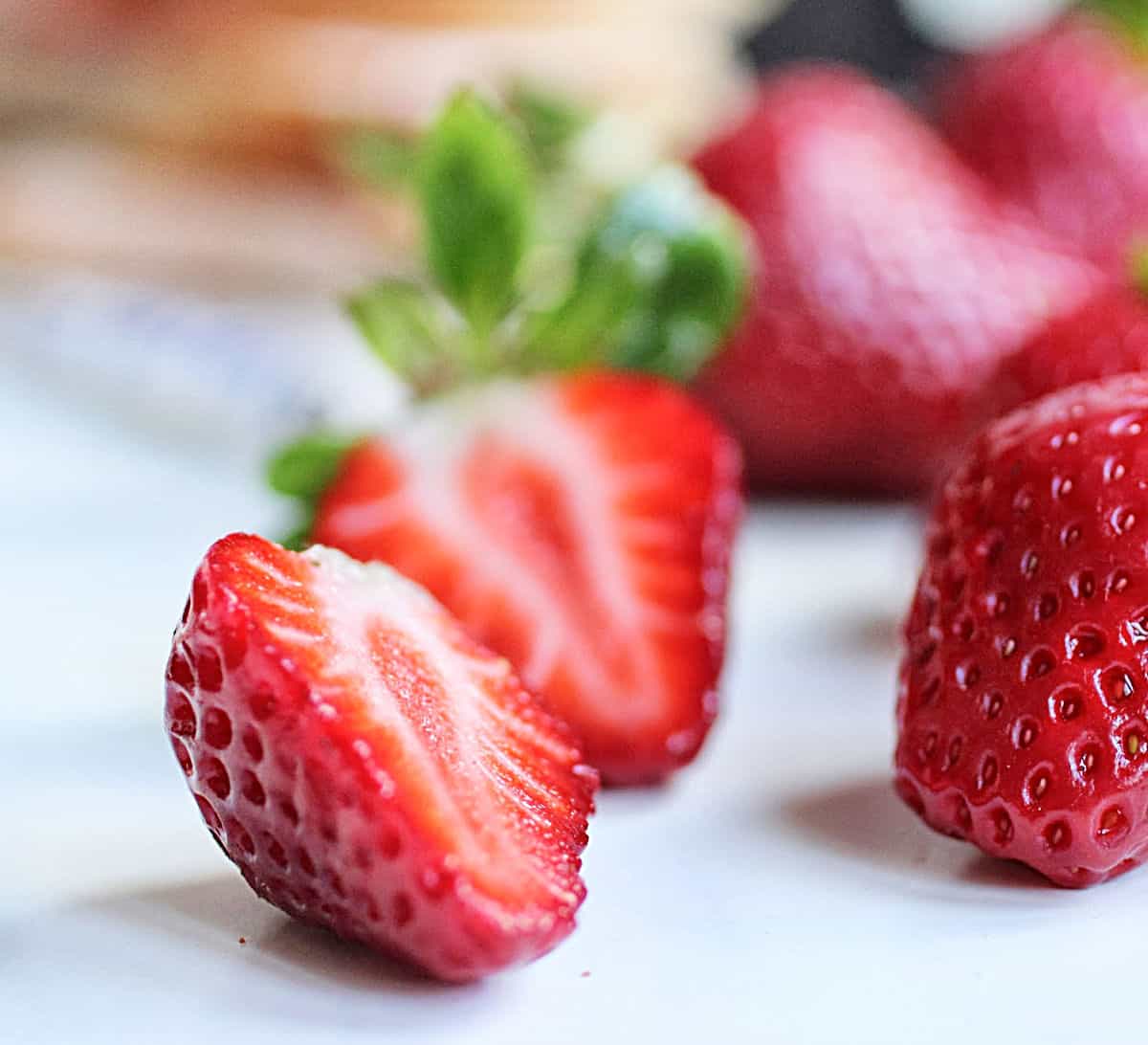 Cut fresh strawberries on white surface