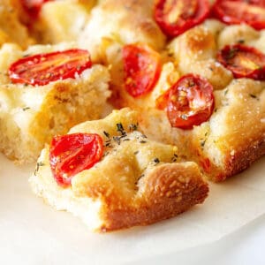 Close up pieces of tomato focaccia on a white plate.