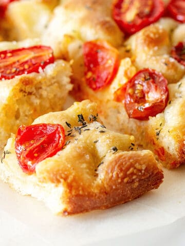 Close up pieces of tomato focaccia on a white plate.