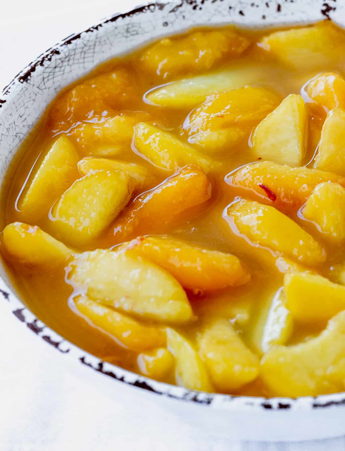 Close up of peach pie filling in white and brown bowl