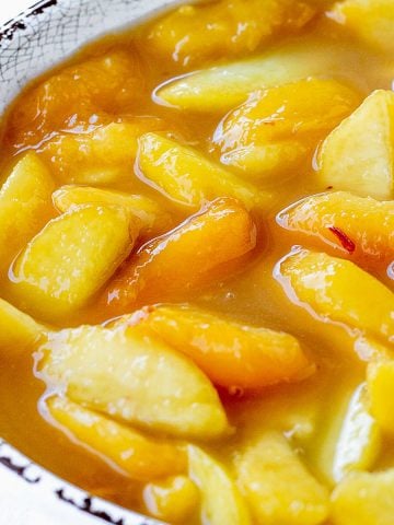 Peach pie filling in white bowl with brown rim.