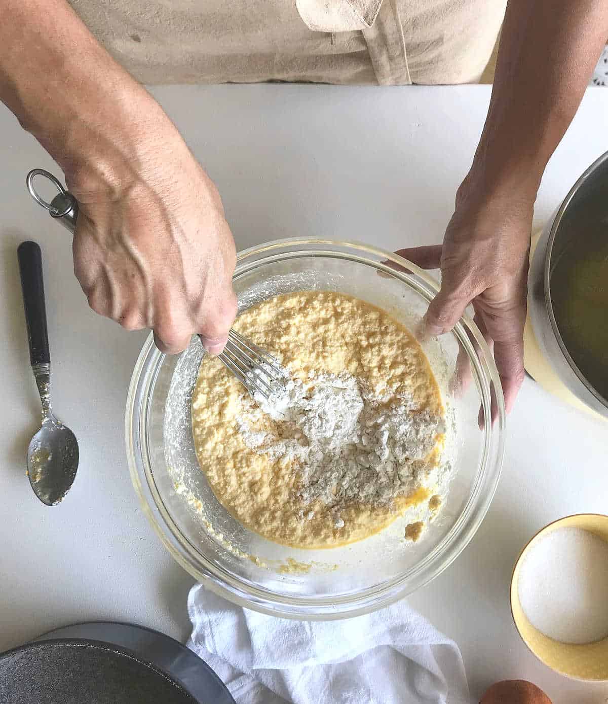 Top view of hands mixing ricotta cheesecake batter in a bowl