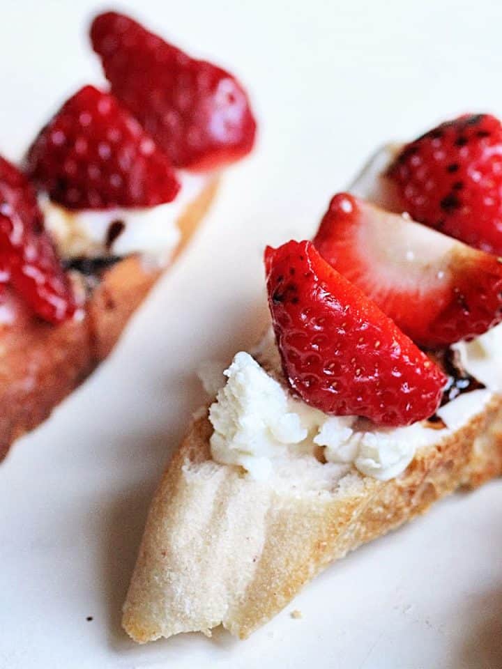 Very close up view of strawberry goat cheese tartine on white table