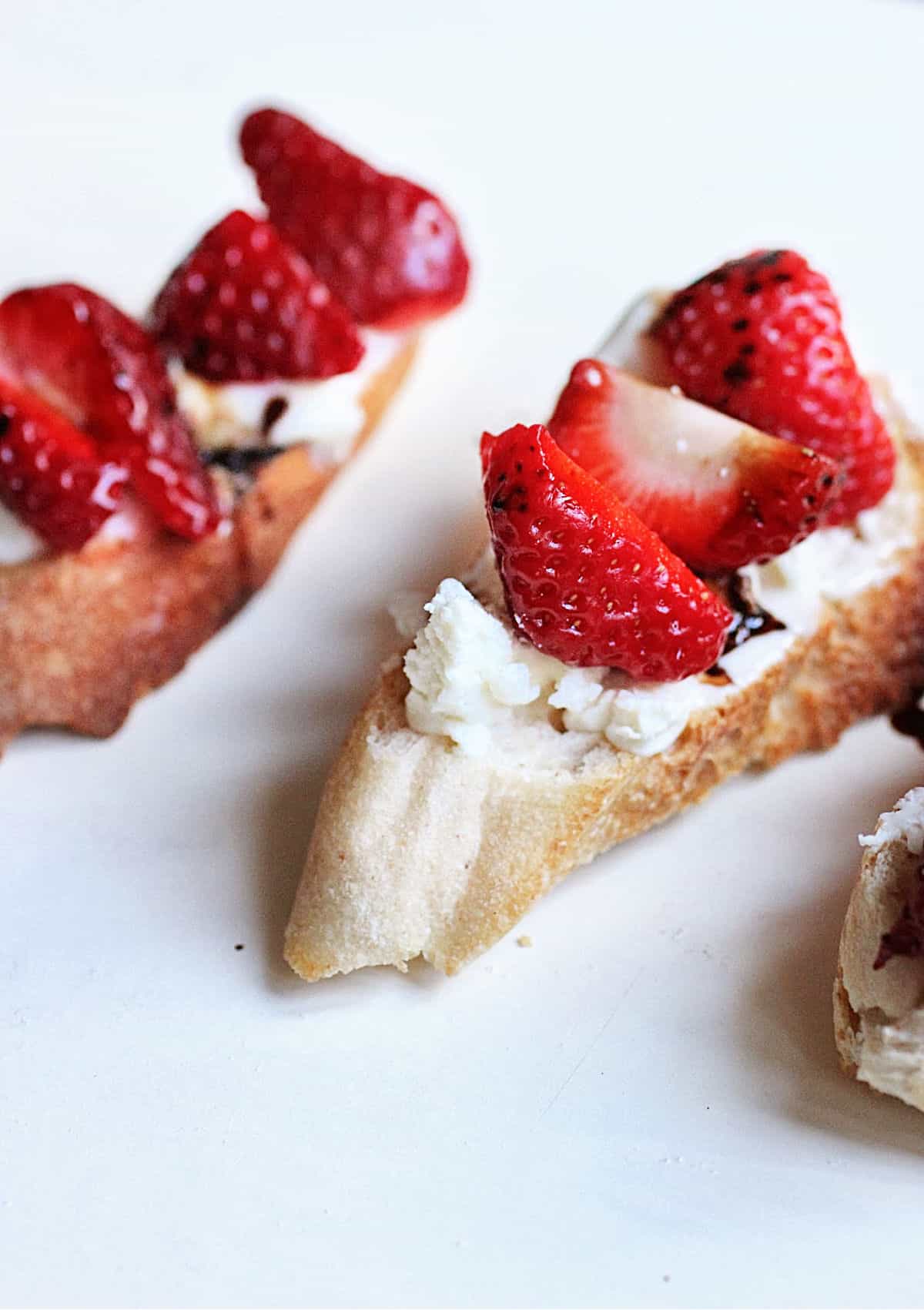 Close up of strawberry tartines on white surface