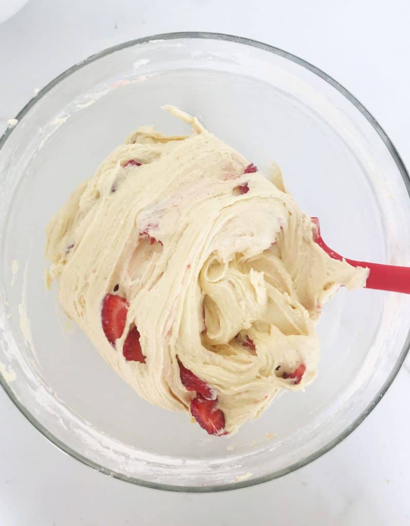 Cake batter with strawberries in a glass bowl. Red spatulavc