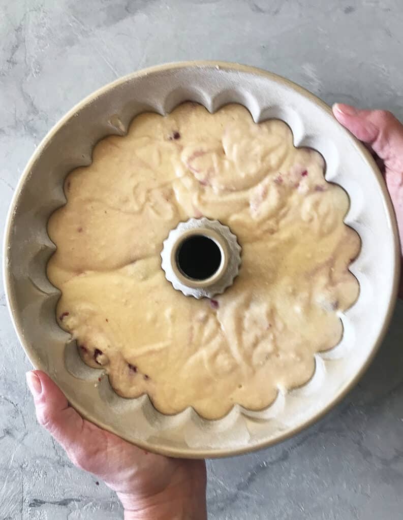 Bundt cake pan with raspberry cake batter. Gray surface. Top view.