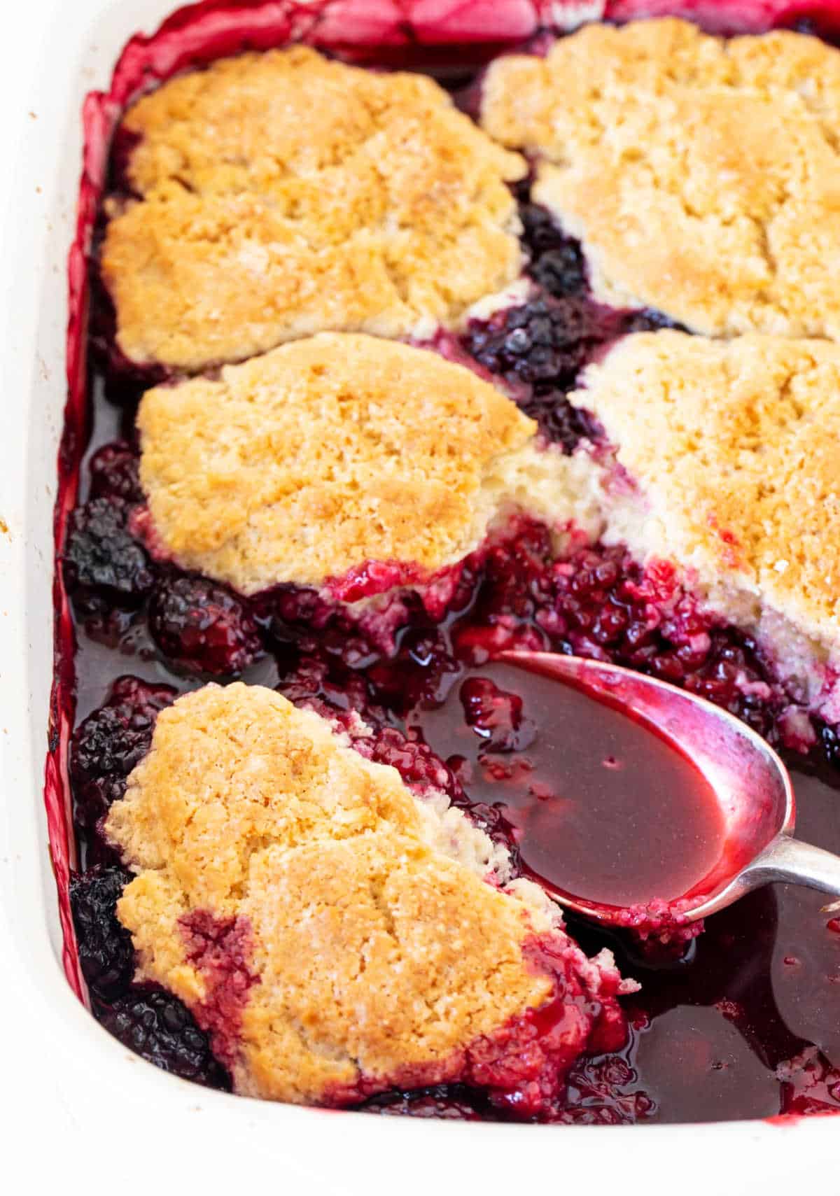 Baked blackberry cobbler with silver spoon inside.