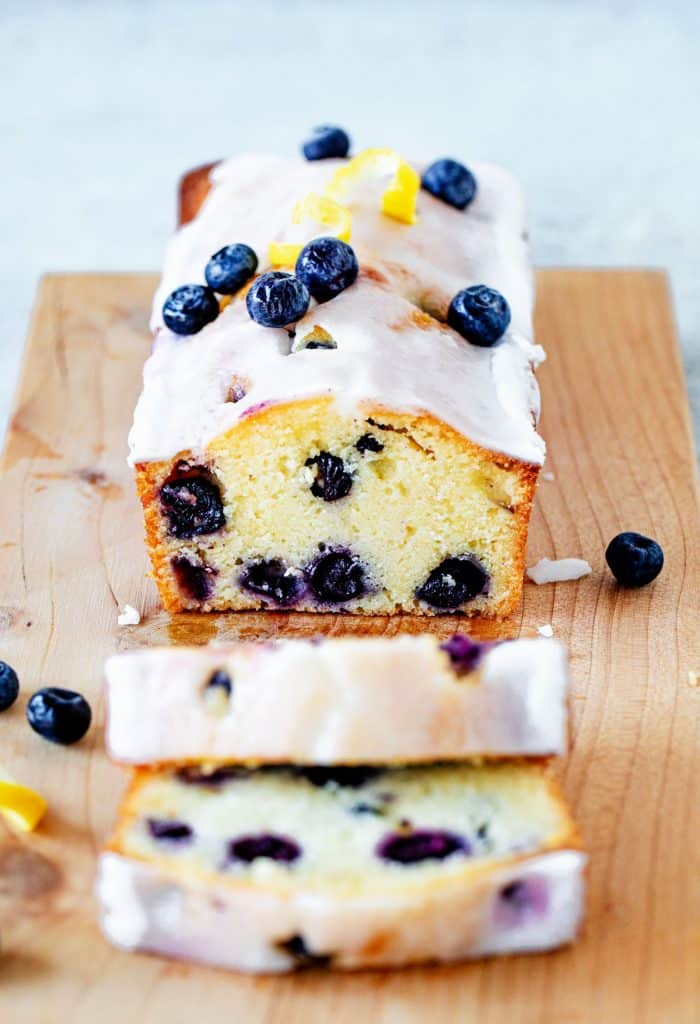 A blueberry pound cake with two cut slices on wooden board