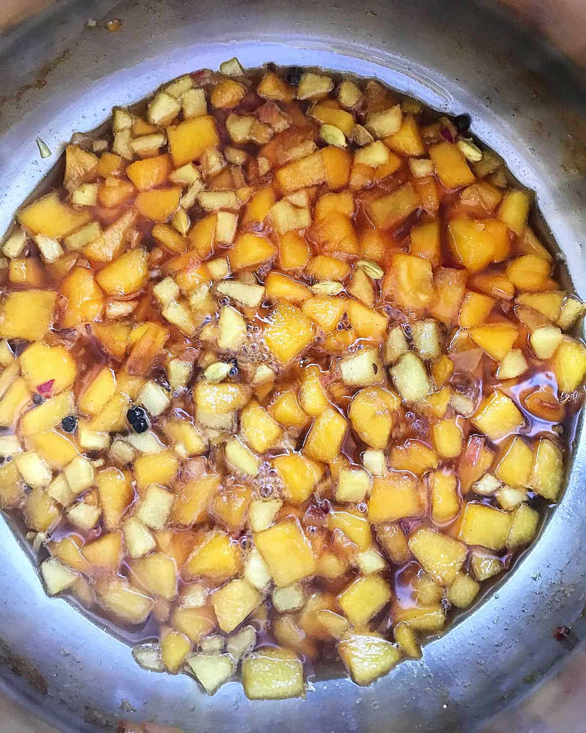 Ingredients for peach chutney in a metal saucepan, view from above.