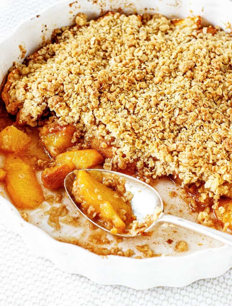 White round dish with peach crisp and silver spoon