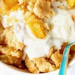 White brown text overlay over close up of peach dump cake with green spoon and ice cream