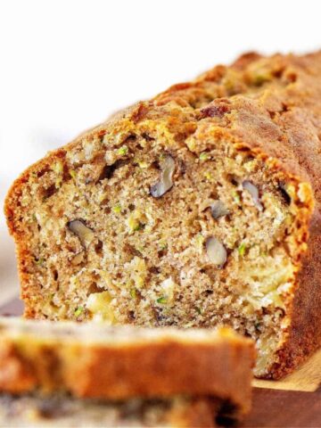Cut loaf of zucchini bread with slices, white background