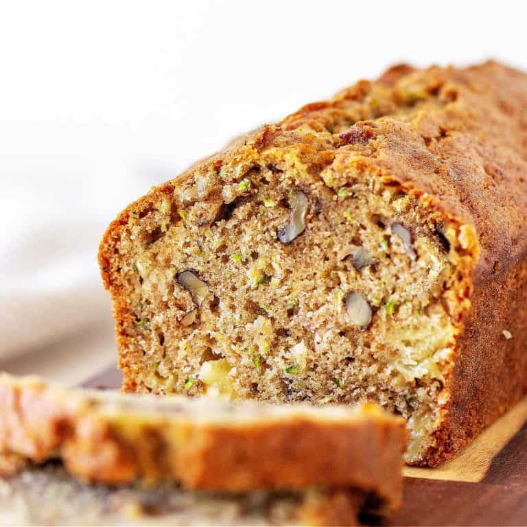 Cut loaf of zucchini bread with slices, white background