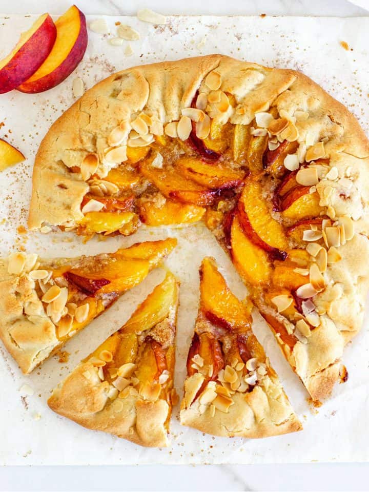 Whole baked peach galette on parchment paper, top view