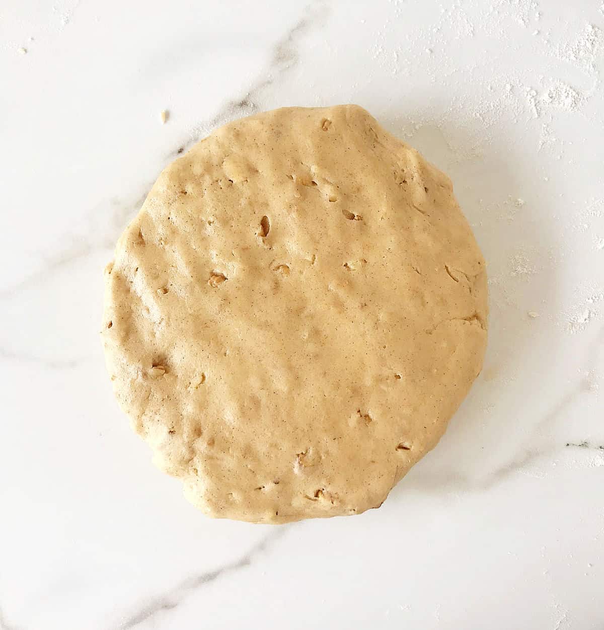 Round of cinnamon dough on a white marble surface