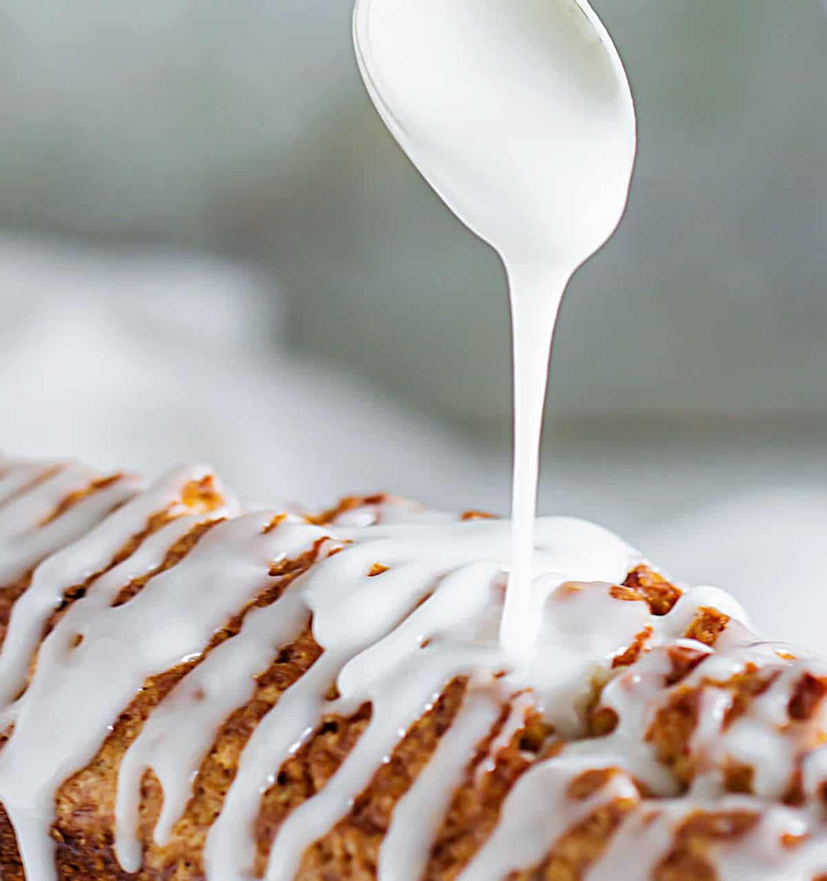 Spoon drizzling powdered sugar glaze on top of cake