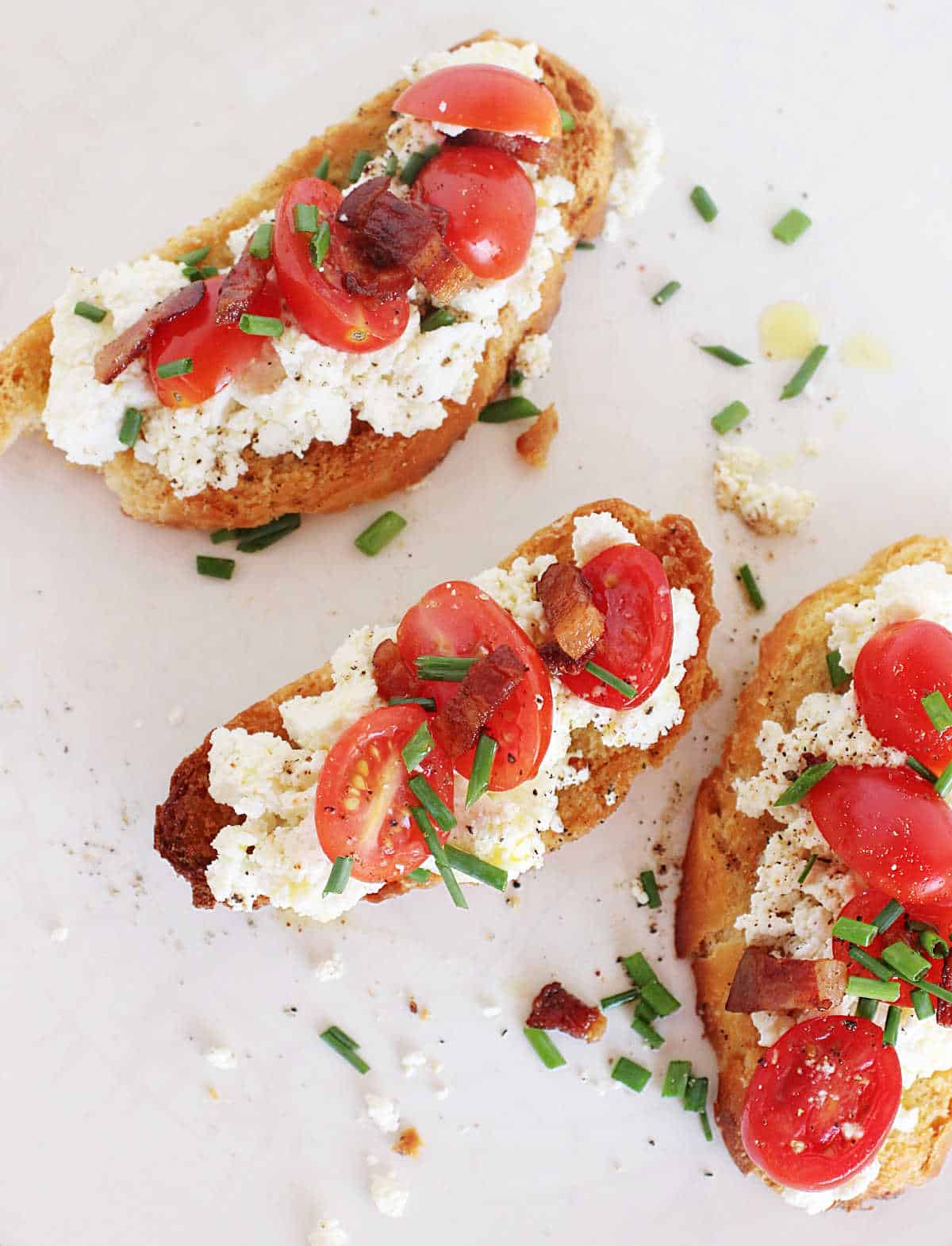 Top view of three ricotta tomato toasts on white plate