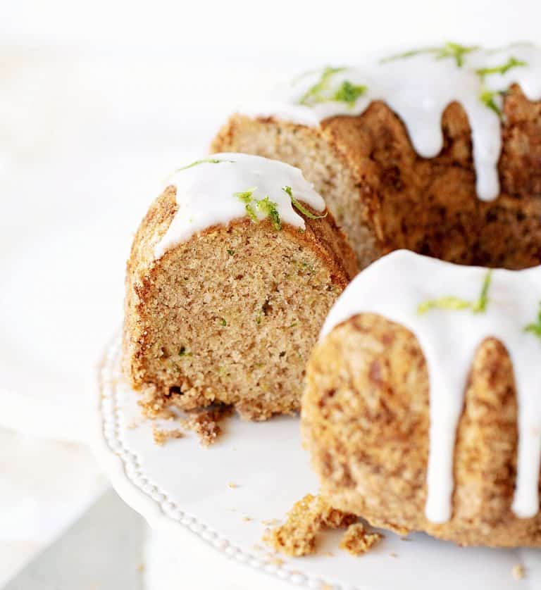 White cake stand with glazed zucchini bundt cake. Partial view with cut slices.