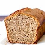 Slanted view of cut applesauce bread on white surface and background