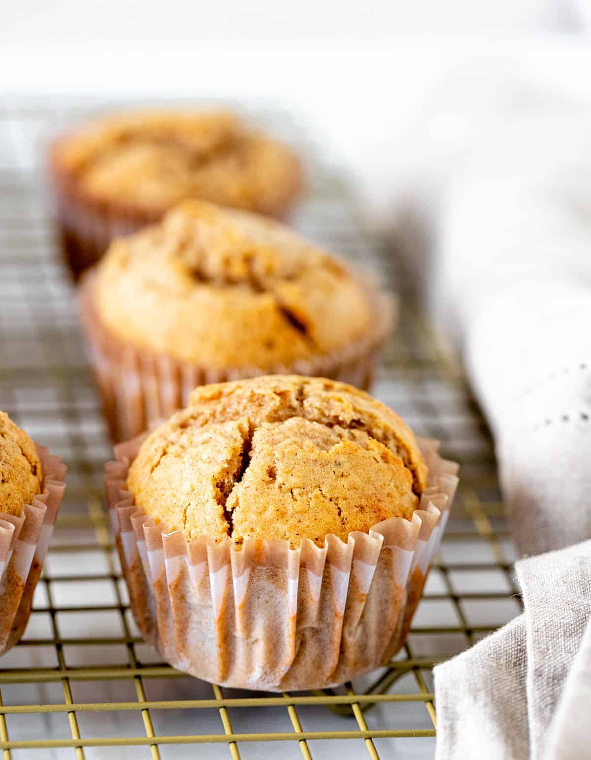 Row of applesauce muffins in paper liners on a wire rack.
