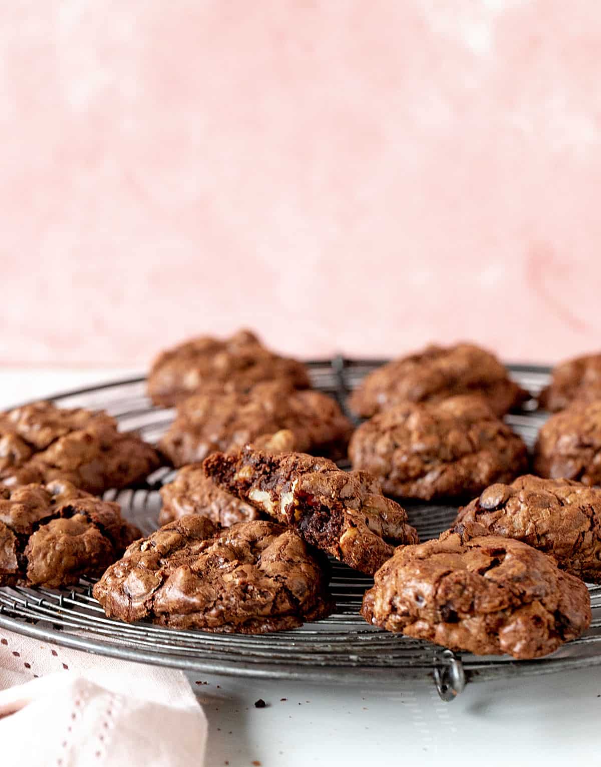 Pink background with chocolate cookies on wire rack.