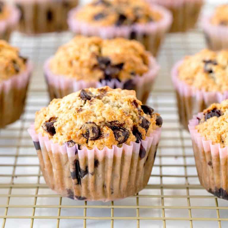 Several oatmeal chocolate chips muffins in paper liners on a wire rack.