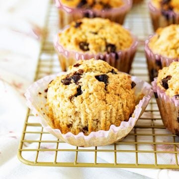 Oatmeal muffins with chips on paper liners on a wire rack.