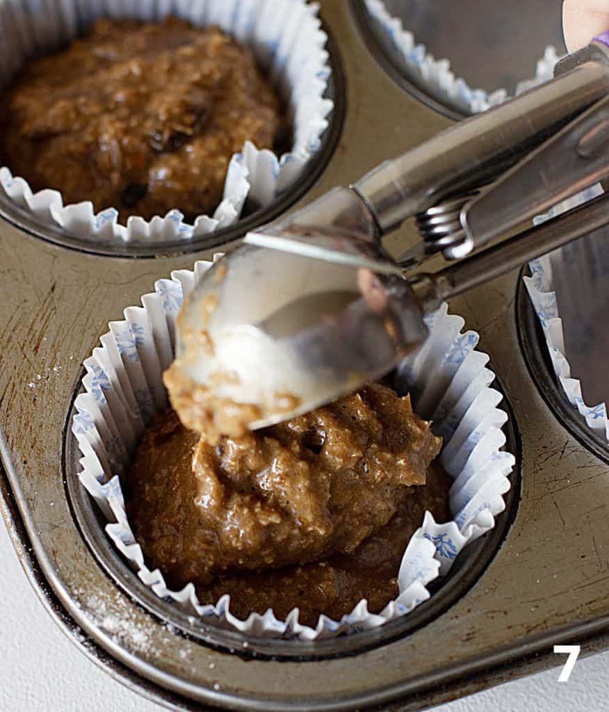 Scooping bran muffin batter with spoon onto muffins paper cups in metal pan