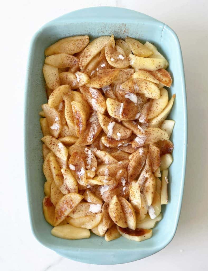 Top view of blue ceramic dish with cooked cinnamon apples for fresh apple dump cake.