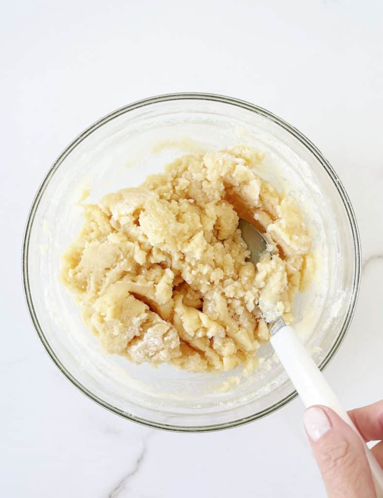 Cake mix and butter topping mixture for caramel apple dump cake in a glass bowl.