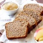 Slices of applesauce bread on a white cloth. Small bowl of applesauce and apple slices.