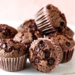 Close up of several chocolate muffins in a mound; white and pink background