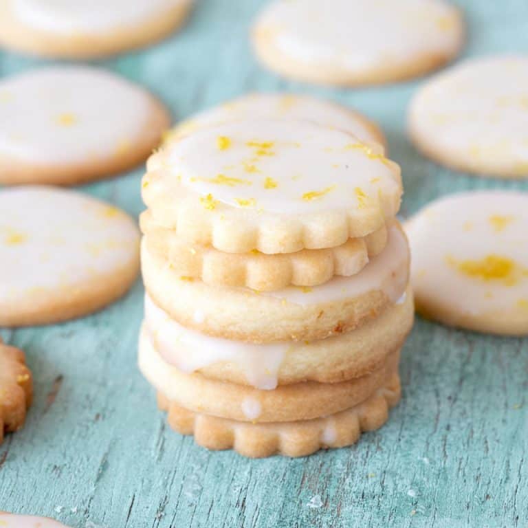 Green wood board with stack and individual lemon glazed cookies.