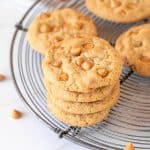 Stack and individual butterscotch cookie son wire rack, white marble surface.