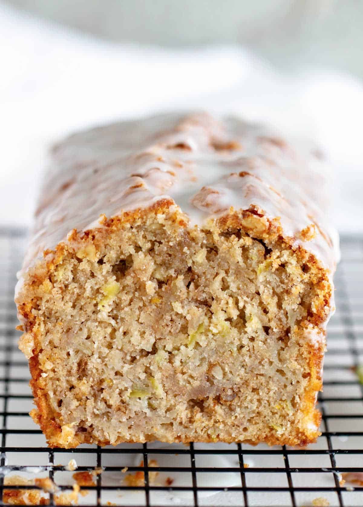 Cut glazed apple loaf cake on wire rack, close up view