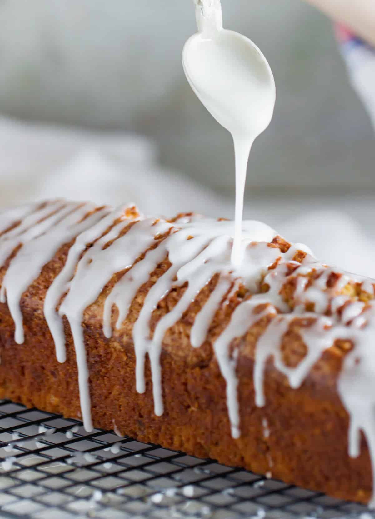 Pouring white glaze from spoon on top of loaf cake