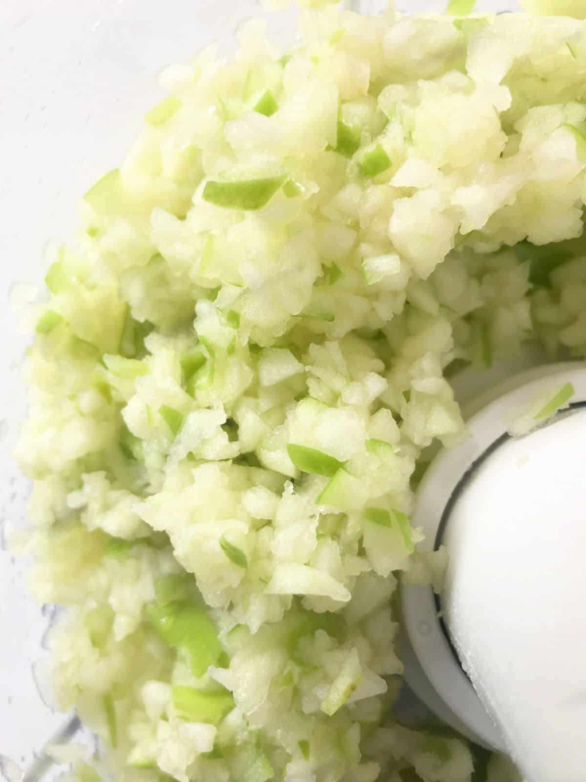 Chopped green apple with skin in food processor bowl