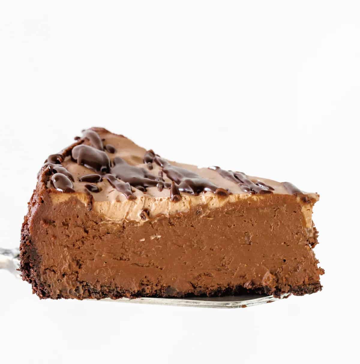 Single slice of chocolate cheesecake on cake server, white background.