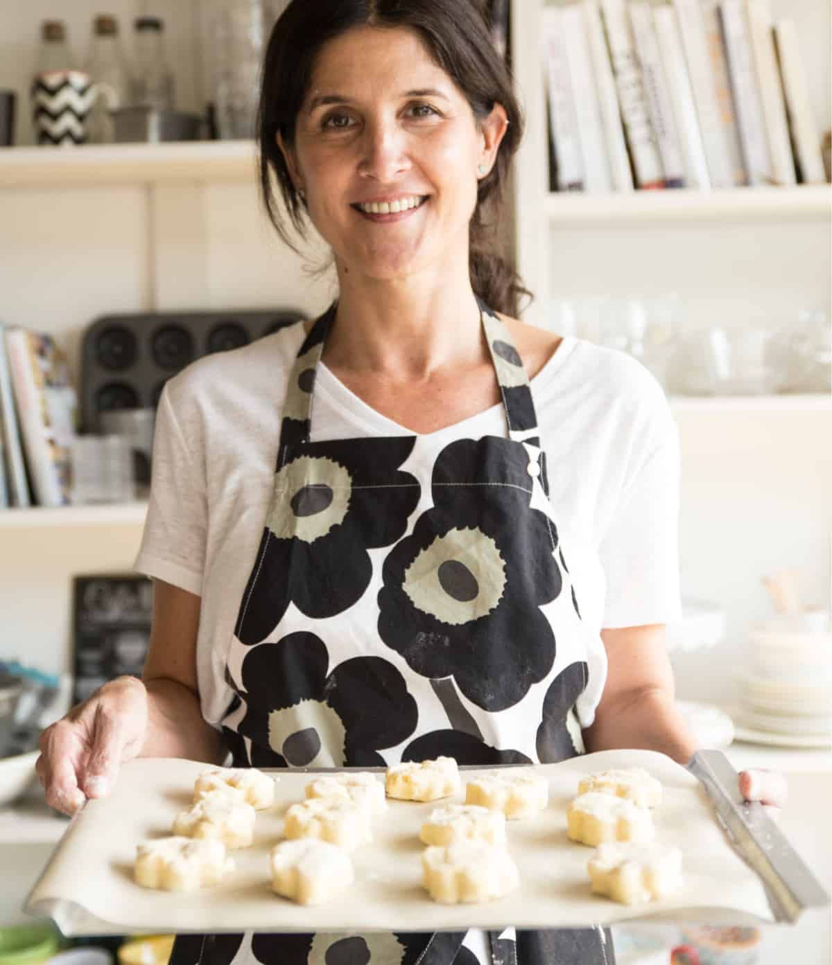 Person with apron and tray of scones
