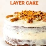 Close up of whole frosted carrot cake on white cake stand, brown orange text overlay.