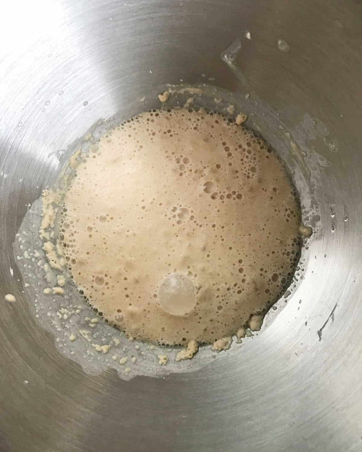 Yeast mixture foaming in a metal stand mixer pan. Close up image.