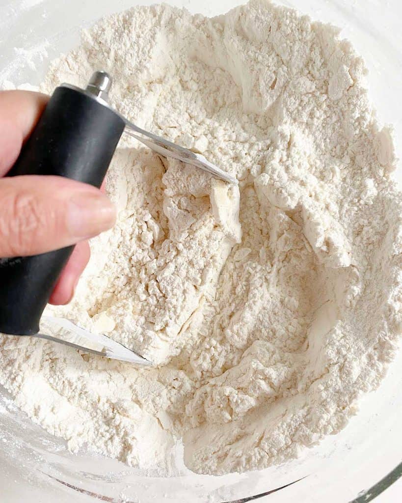 Cutting butter into flour mixture with a pastry cutter.