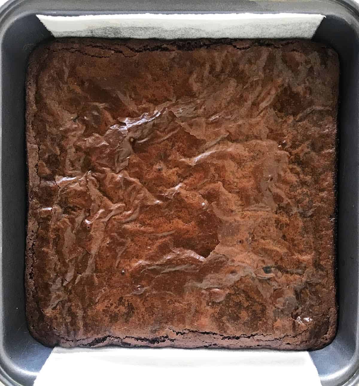 Metal pan with baked brownie wit crackly crust.
