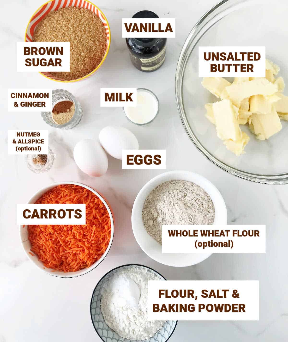 Carrot cake ingredients in small bowls on white surface, including brown sugar, vanilla, grated carrots and spices.