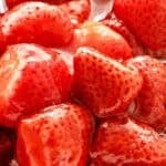 Red and white text overlay on strawberry compote close up.