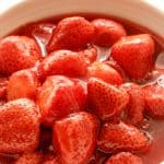Close up of strawberry compote on white bowl; red text overlay.