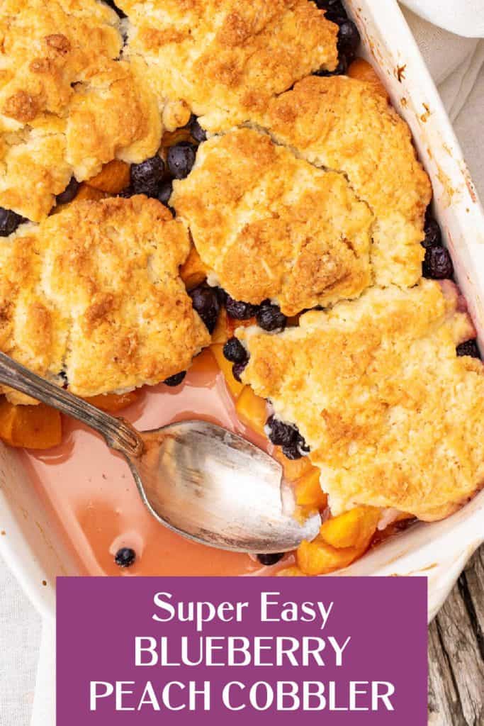Whole peach blueberry cobbler dish missing a serving, silver spoon inside, purple text overlay.