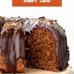 Orange white text overlay on cut chocolate glazed bundt cake on pinkish cake stand.