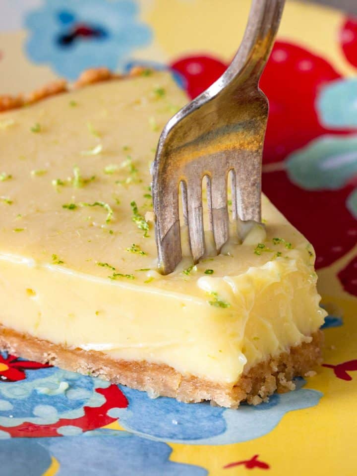 Slice of key lime pie and silver fork on a colorful plate.
