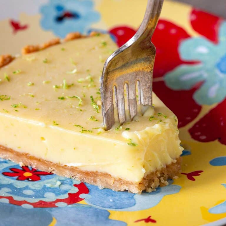 Slice of key lime pie and silver fork on a colorful plate.